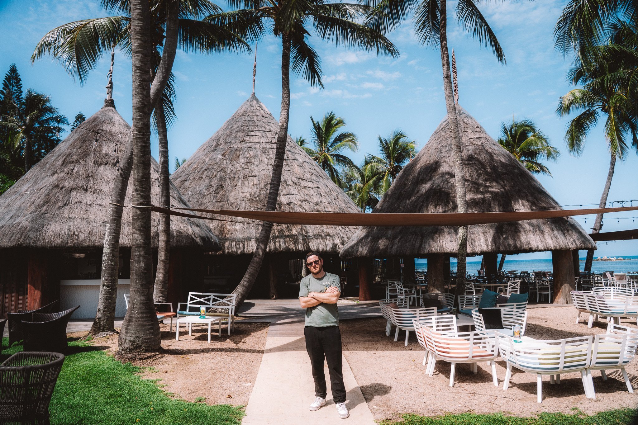 Herr Krank in front of the hotel's Kanak-style cases under palm trees